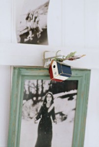 A detail of a black and white photograph of a woman in a painted frame, bird house trinket,