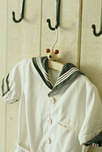 A detail of a child’s, old fashioned sailor suit hanging from wrought iron hook
